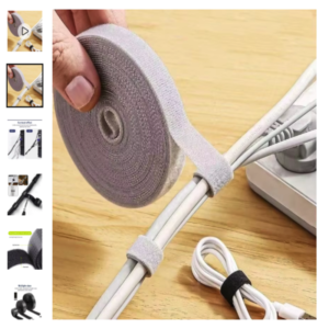 Cinta enrolladora organizadora de cables de velcro Mano sosteniendo un rollo de cinta de velcro gris organizando un fajo de cables blancos