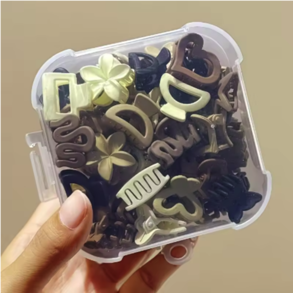 Set de pinzas de pelo pequeñas en tonos marrones y beige dentro de su caja organizadora transparente