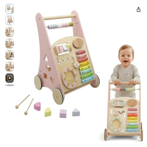 Andador interactivo de madera Montessori de Buddy Baby. Andador de Madera Montessori Buddy Baby de color rosa pastel y madera natural junto a un bebé sonriente de perfil empujándolo.