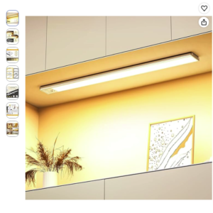 Luz de armario con sensor de movimiento recargable OUILA Luz de armario con sensor de movimiento OUILA de 41cm encendida bajo un mueble de cocina moderno proyectando luz cálida sobre la pared.